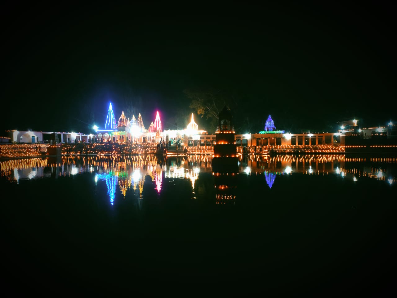 Temple lit with lights, reflected in the water at night